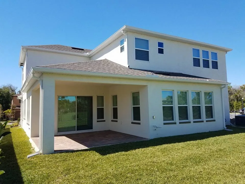 Rear two story cream stucco white gutters paver patio, Sanford